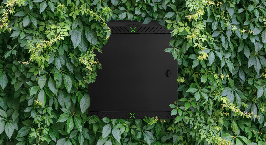 X-Rack vægmonteret kabinet titter frem fra en grøn busk