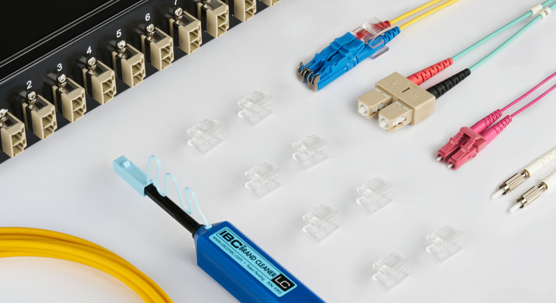 Netzwerkkomponenten und Werkzeuge, darunter LWL-Patchkabel und Werkzeuge, darunter ein Patchpanel, LWL-Patchkabel, farbige Kabel und ein Abisolierwerkzeug.