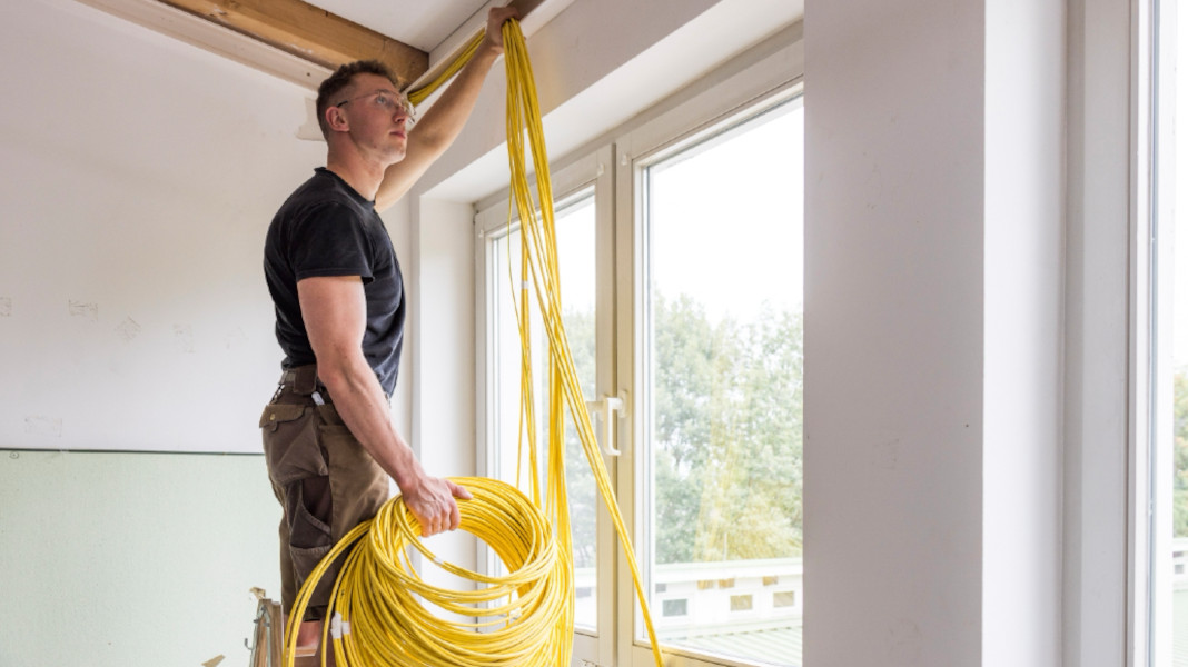 Håndværker lægger gule netværkskabler i loftet - professionel installation af strukturerede it-k