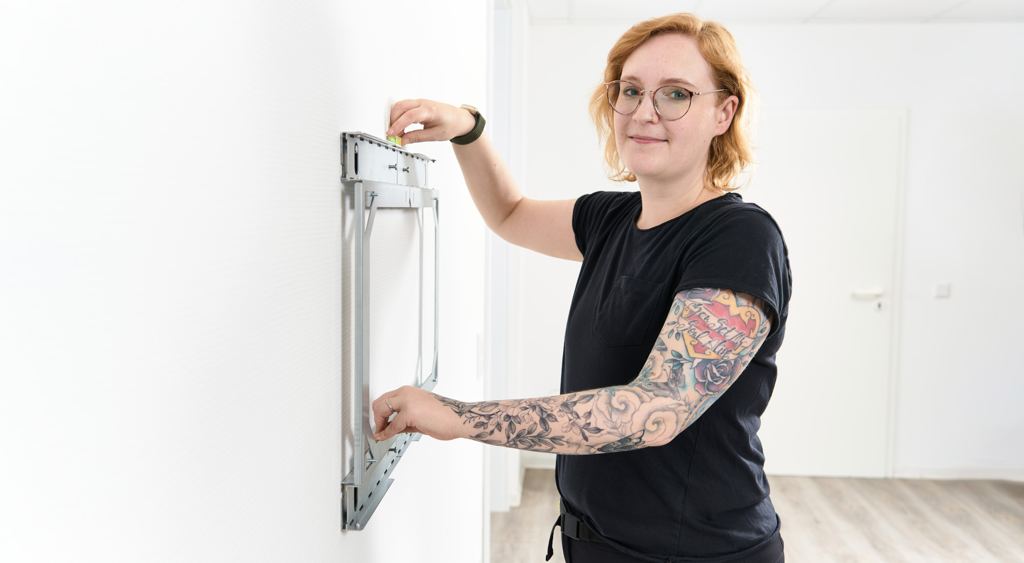 Kvinden kontrollerer ophængningen af X-Rack med det medfølgende vaterpas. Kvinden kontrollerer ophængningen af X-Rack med det medfølgende vaterpas.