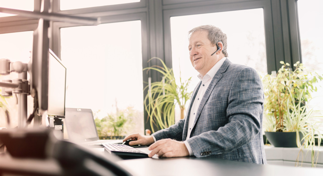 Konsulent med headset på arbejde ved computeren - supply chain management hos EFB-Elektronik