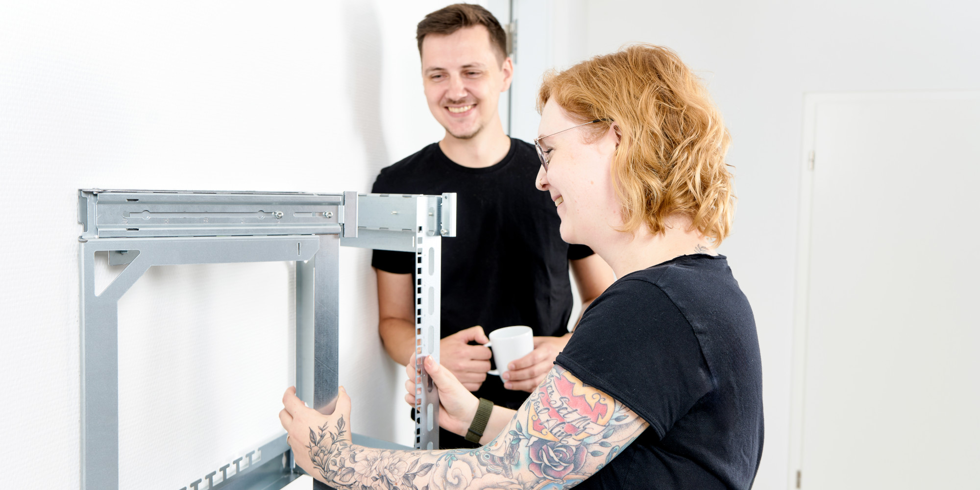 Kvinde folder X-Rack ud, mens hendes kollega drikker kaffe Kvinde folder X-Rack ud, mens hendes kollega drikker kaffe