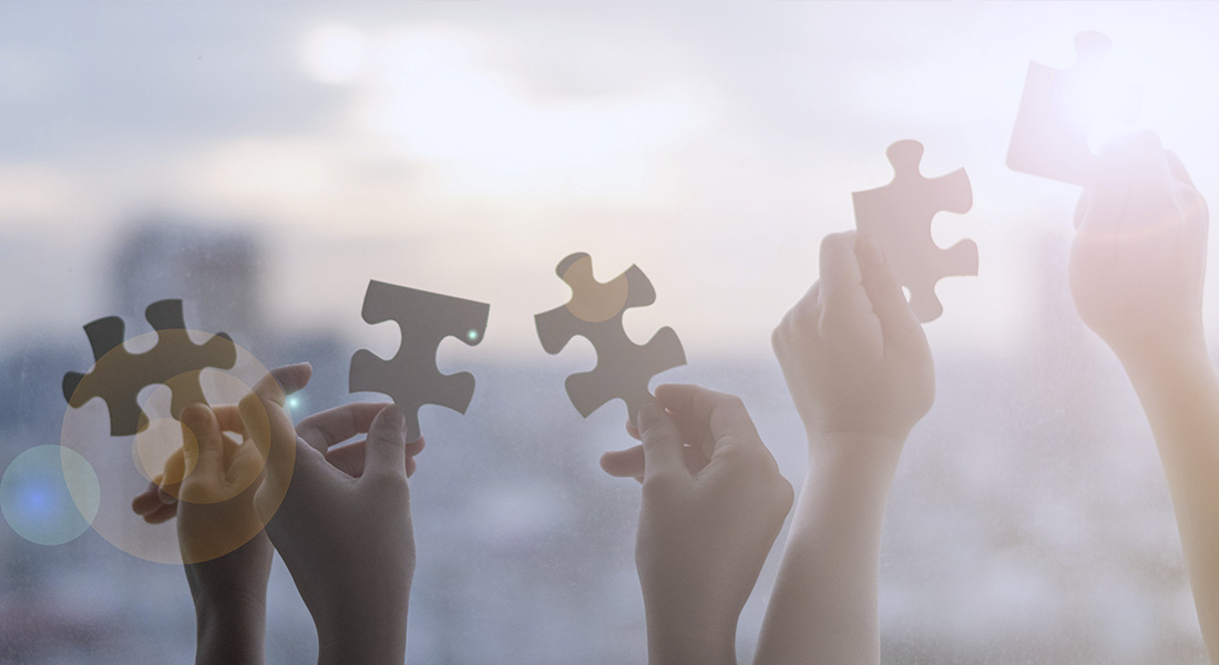 Fünf Hände halten jeweils ein Puzzleteil in die Höhe Fünf Hände halten jeweils ein Puzzleteil in die Höhe